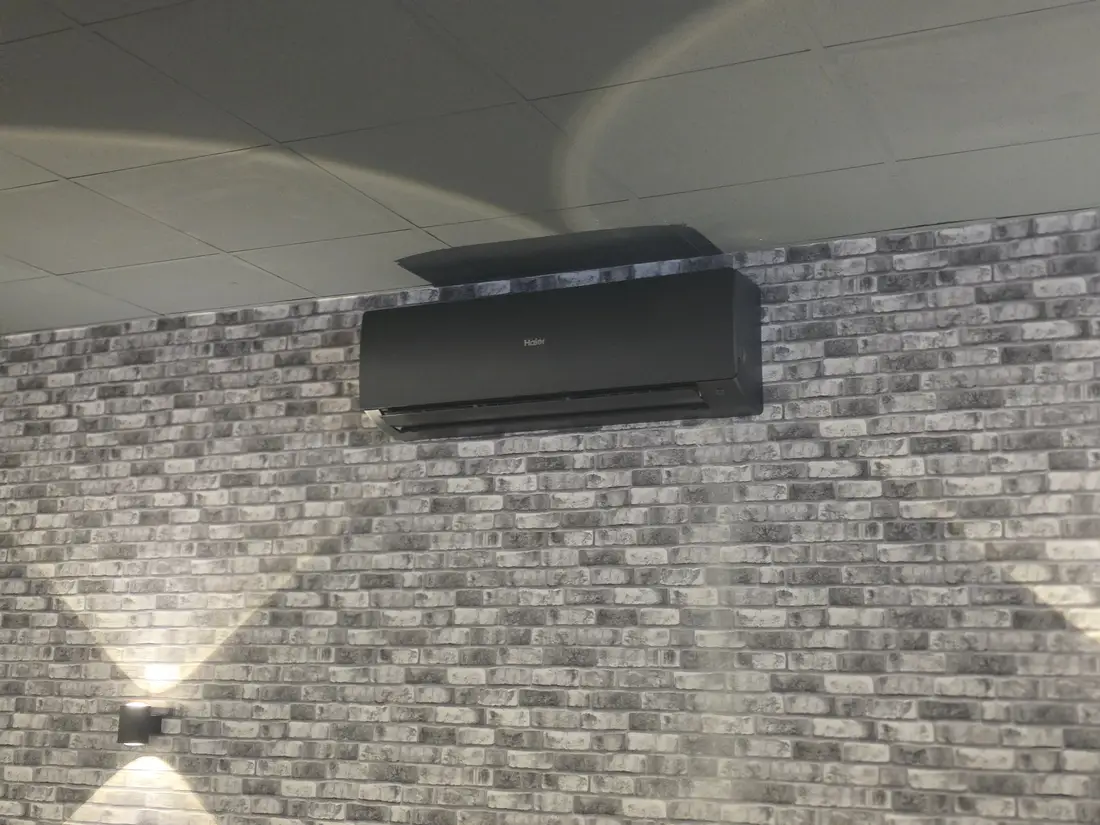 Schwarzes Haier Klimagerät an Backsteinwand